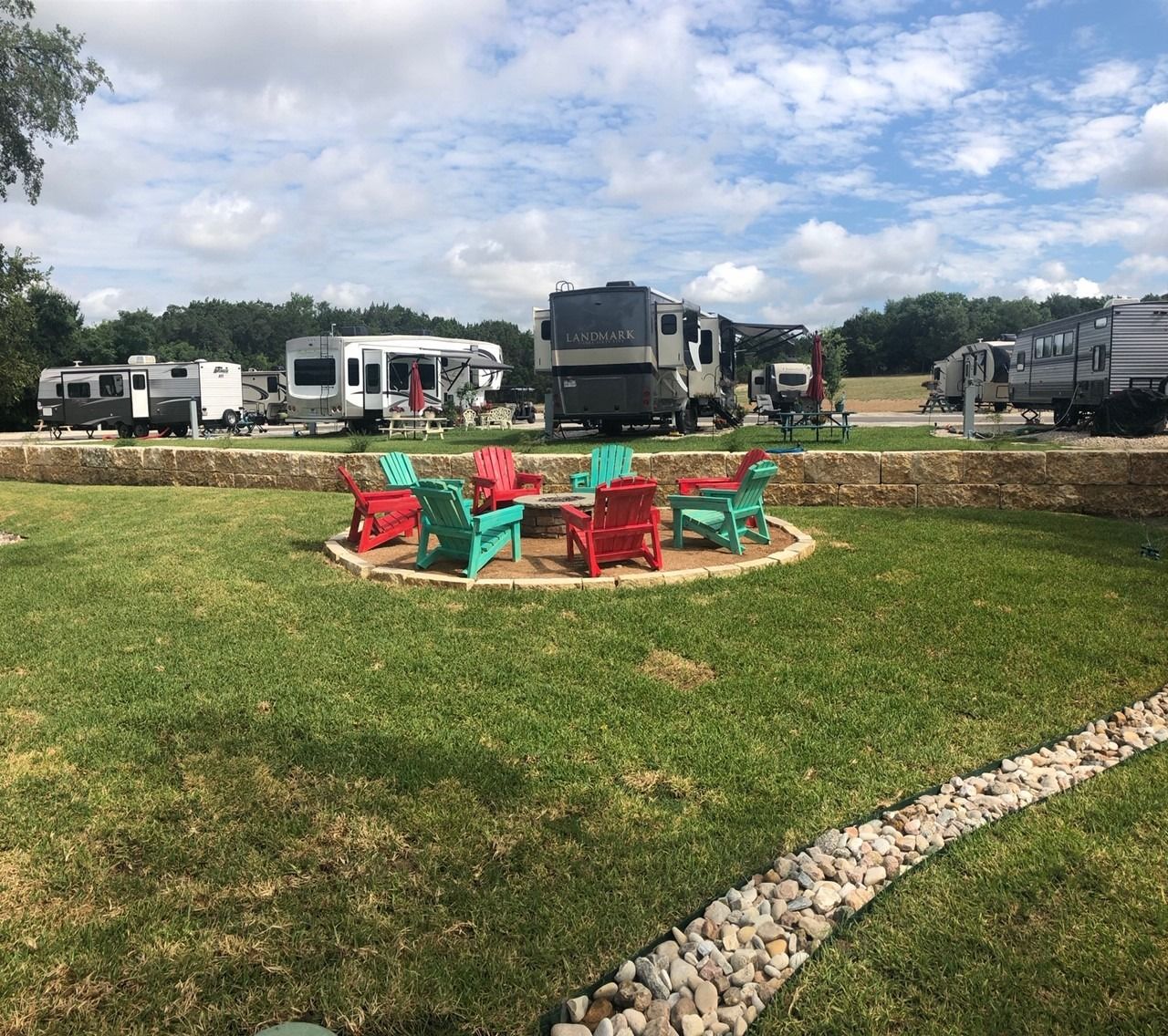 A group of chairs are sitting around a fire pit in a park.
