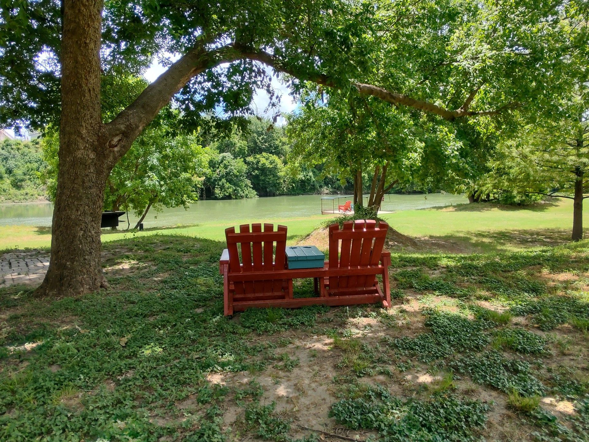 A wooden deck with two chairs on it next to a river.