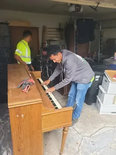 A man is playing a piano in a garage.