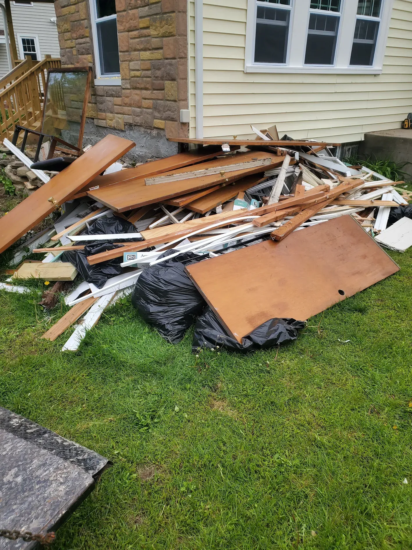A pile of wood is sitting on the grass in front of a house.