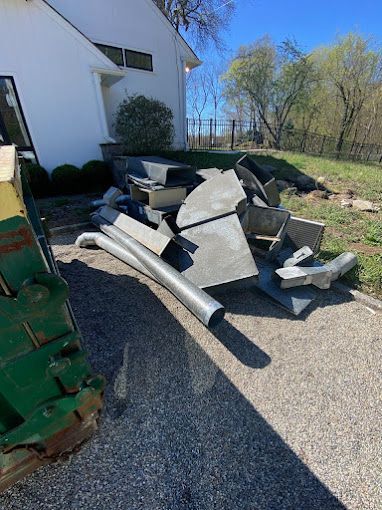 A pile of junk is sitting on the side of the road in front of a house.