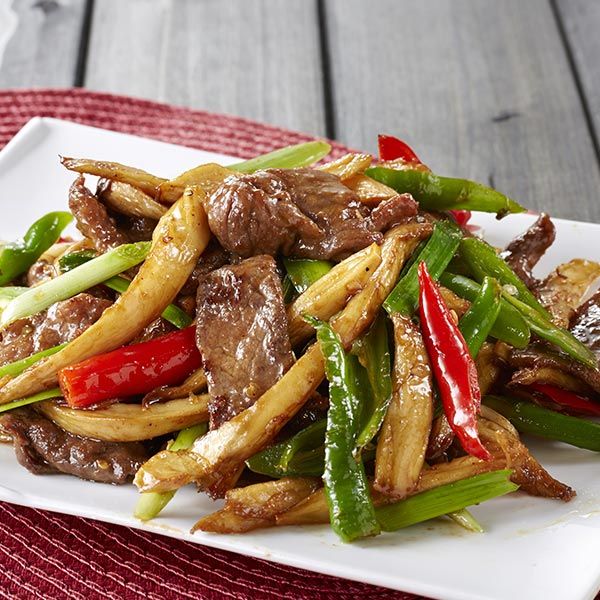 A white plate topped with meat and vegetables on a table
