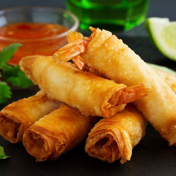 Fried shrimp rolls are stacked on top of each other on a table.