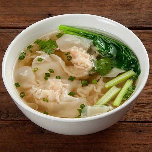 A bowl of wonton soup on a wooden table
