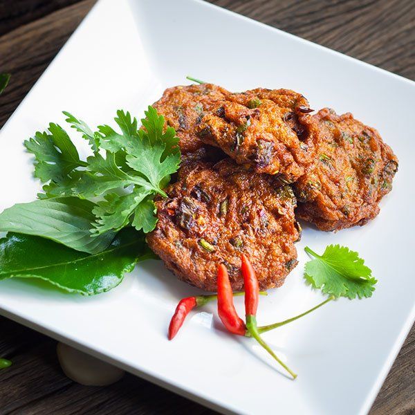 A white plate topped with fried food and vegetables on a wooden table.