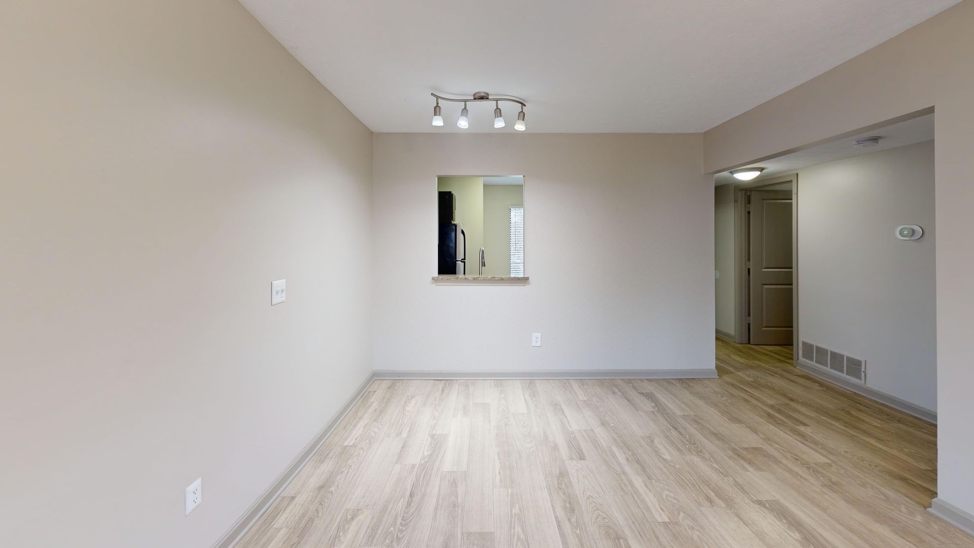 A dining room with a table and chairs and a picture on the wall.