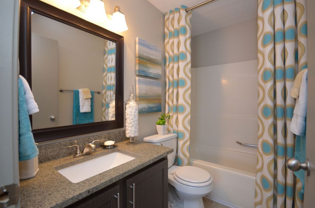 A bathroom with a sink , toilet , bathtub and mirror.