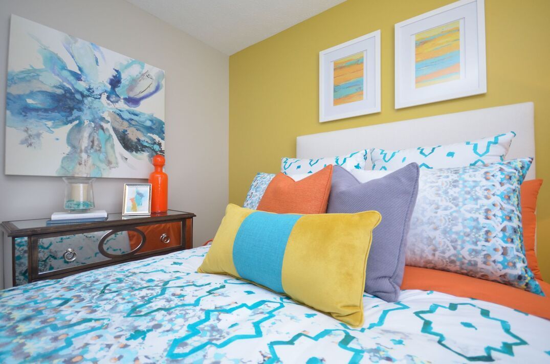 A bedroom with a bed , nightstand , pillows and a painting on the wall.