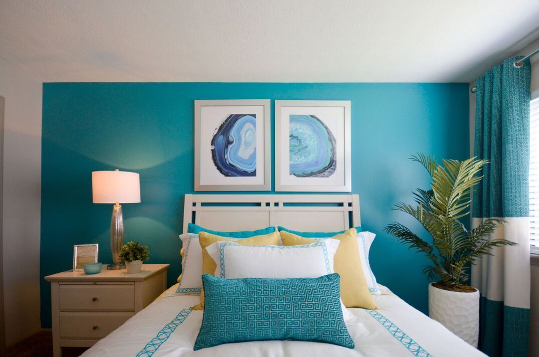 A bedroom with blue walls and a bed with blue pillows