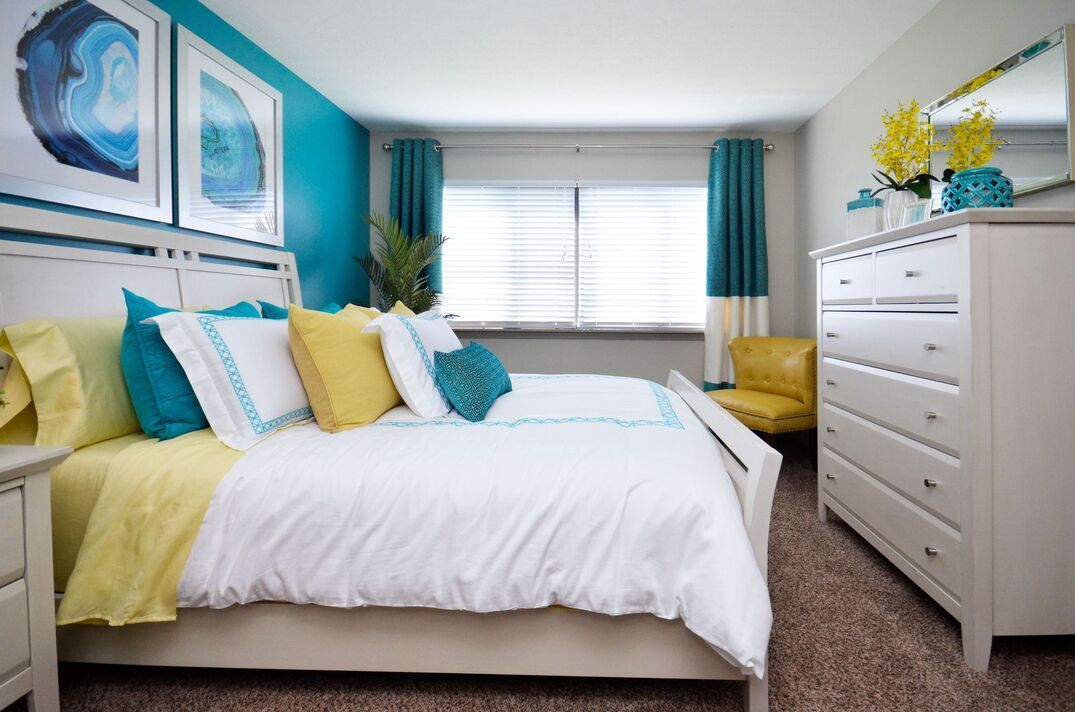 A bedroom with a bed , dresser , nightstand and chair.