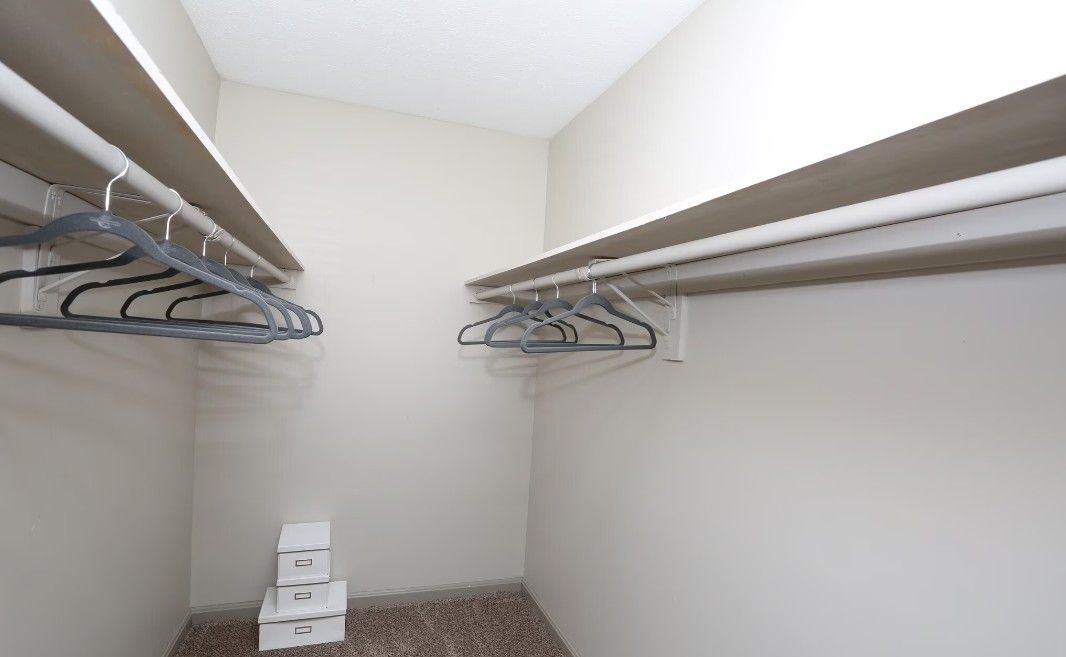 A walk in closet with a lot of clothes hanging on the racks.