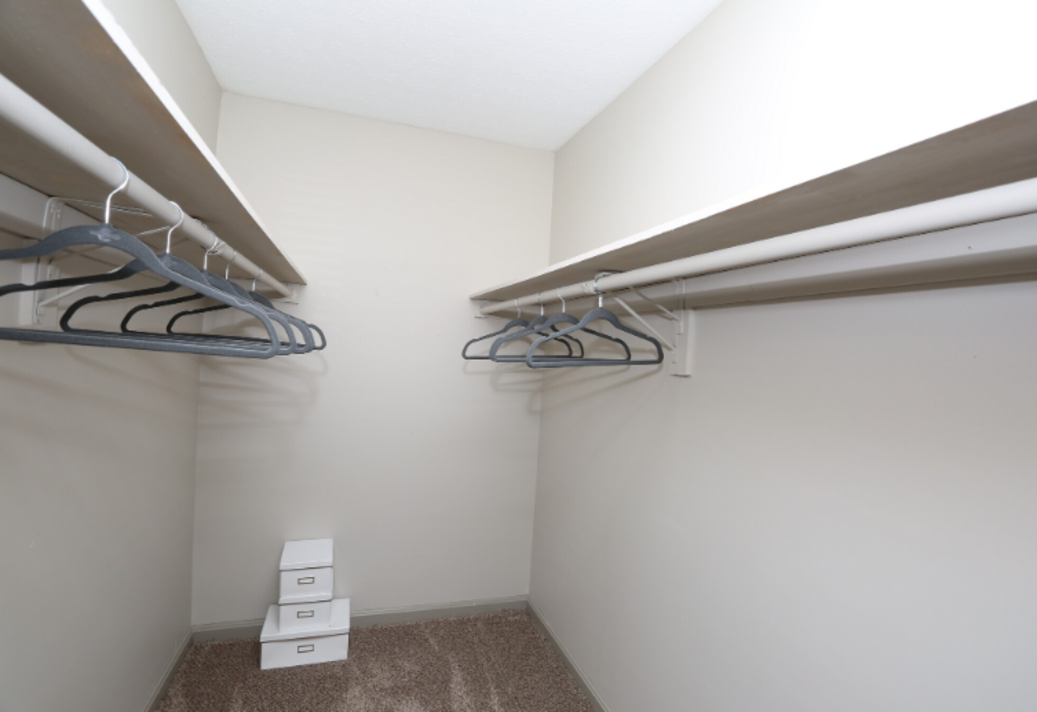 A walk in closet with a lot of clothes hanging on the shelves