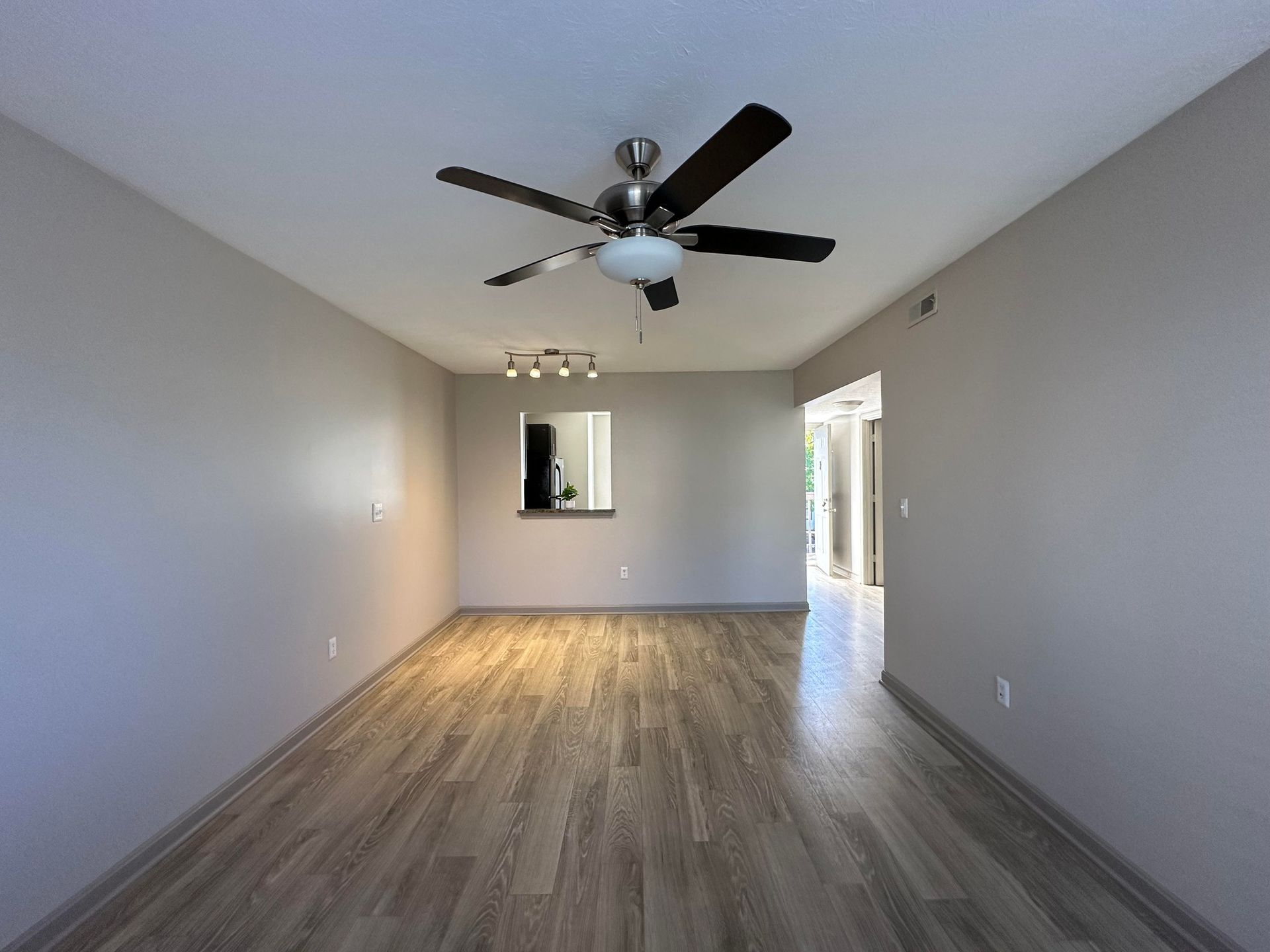An empty living room with a ceiling fan and a mirror