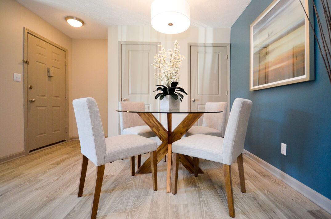 A dining room with a table and chairs and a picture on the wall.