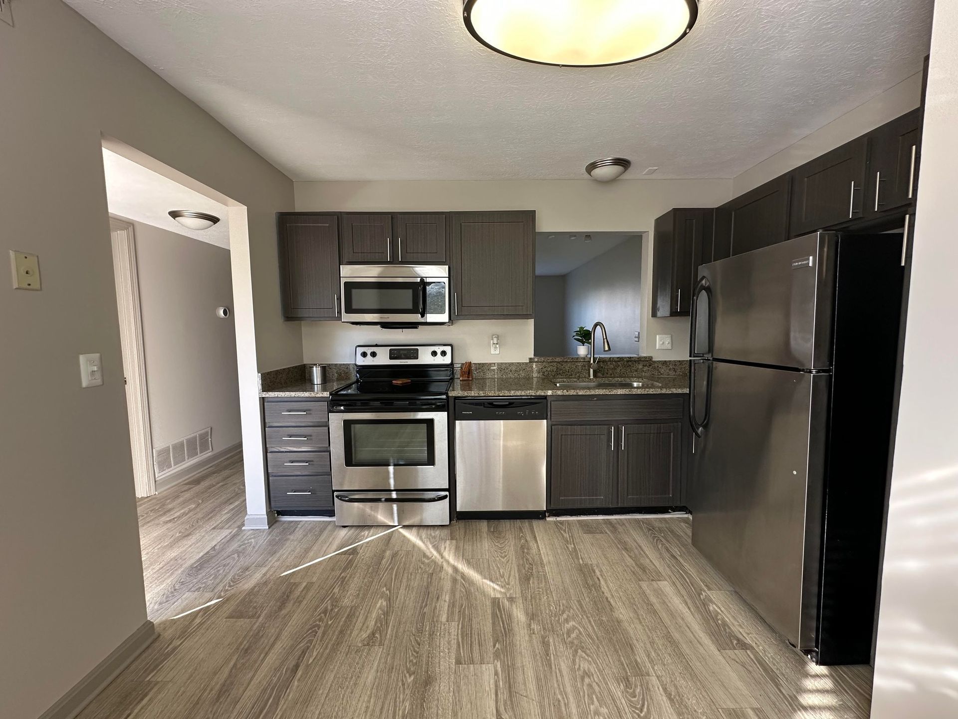 A kitchen with stainless steel appliances and wooden floors.