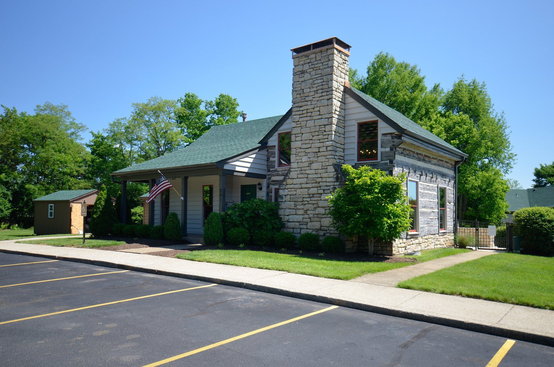 A stone house with a green roof and a chimney