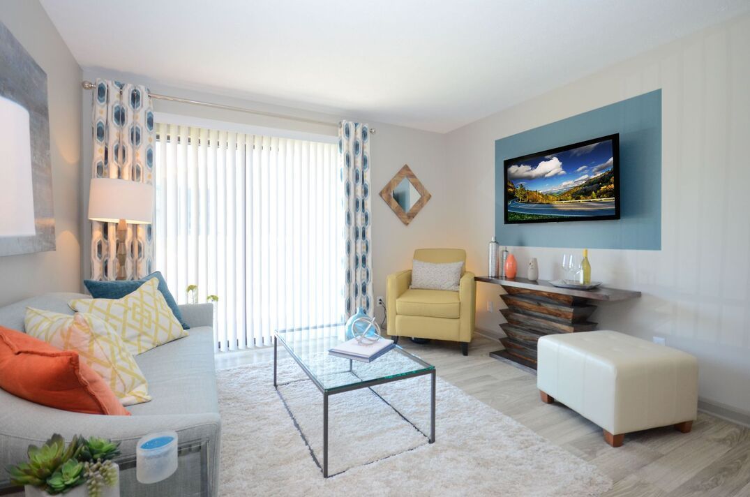 A living room with a couch , chair , coffee table and television.