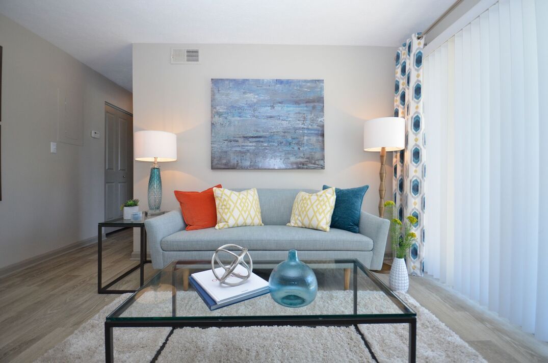 A living room with a couch , coffee table , lamps and a painting on the wall.