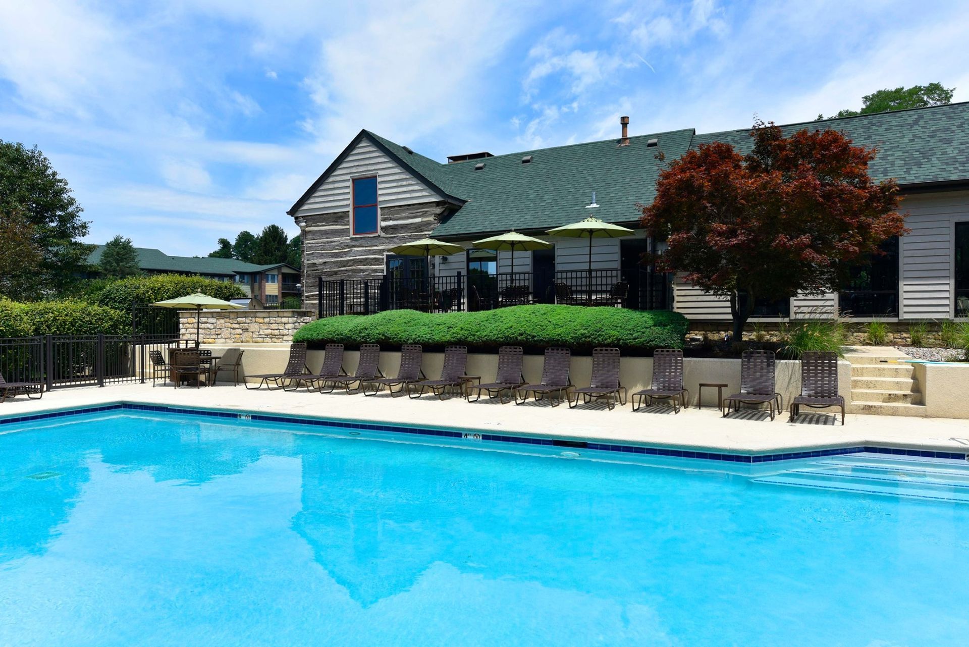 A large swimming pool with chairs and umbrellas in front of a house.