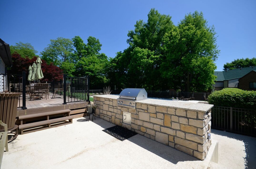 A brick wall with a grill on it in the backyard of a house.