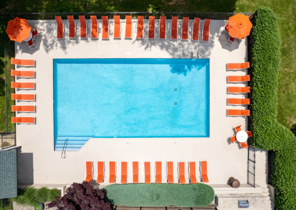 An aerial view of a large swimming pool surrounded by orange chairs and umbrellas.