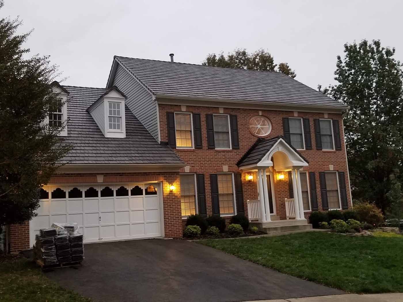 Two-story brick house with a dark gray roof, white trim, and a two-car garage.
