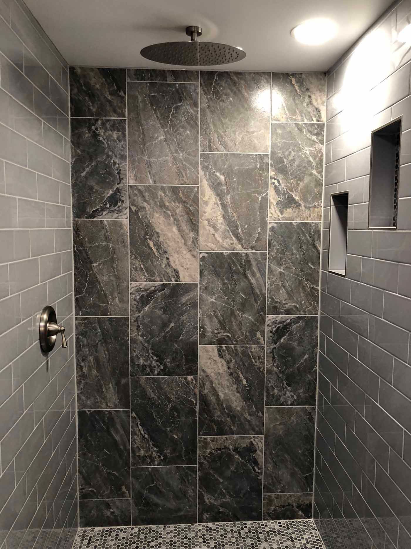 Shower with dark gray tile walls, including a patterned accent wall, and a circular rain shower head.
