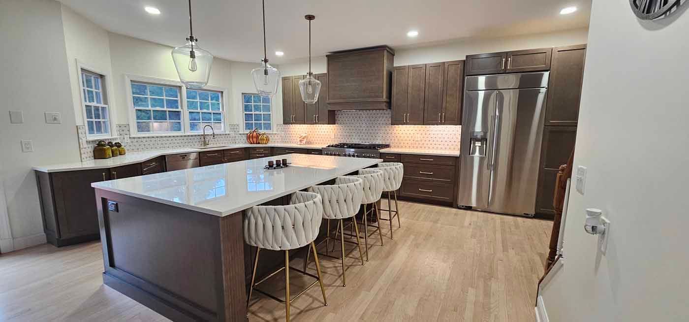 Modern kitchen with a large island, dark cabinets, and stainless steel appliances.
