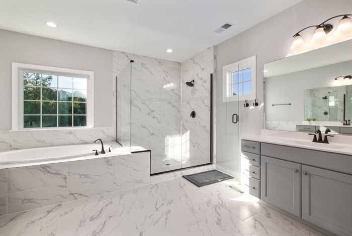 Spacious, modern bathroom with marble tile, glass shower, soaking tub, and double vanity.