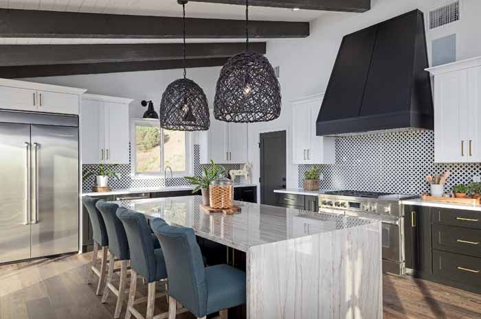Modern kitchen with large island, black and white accents, and decorative pendant lights.