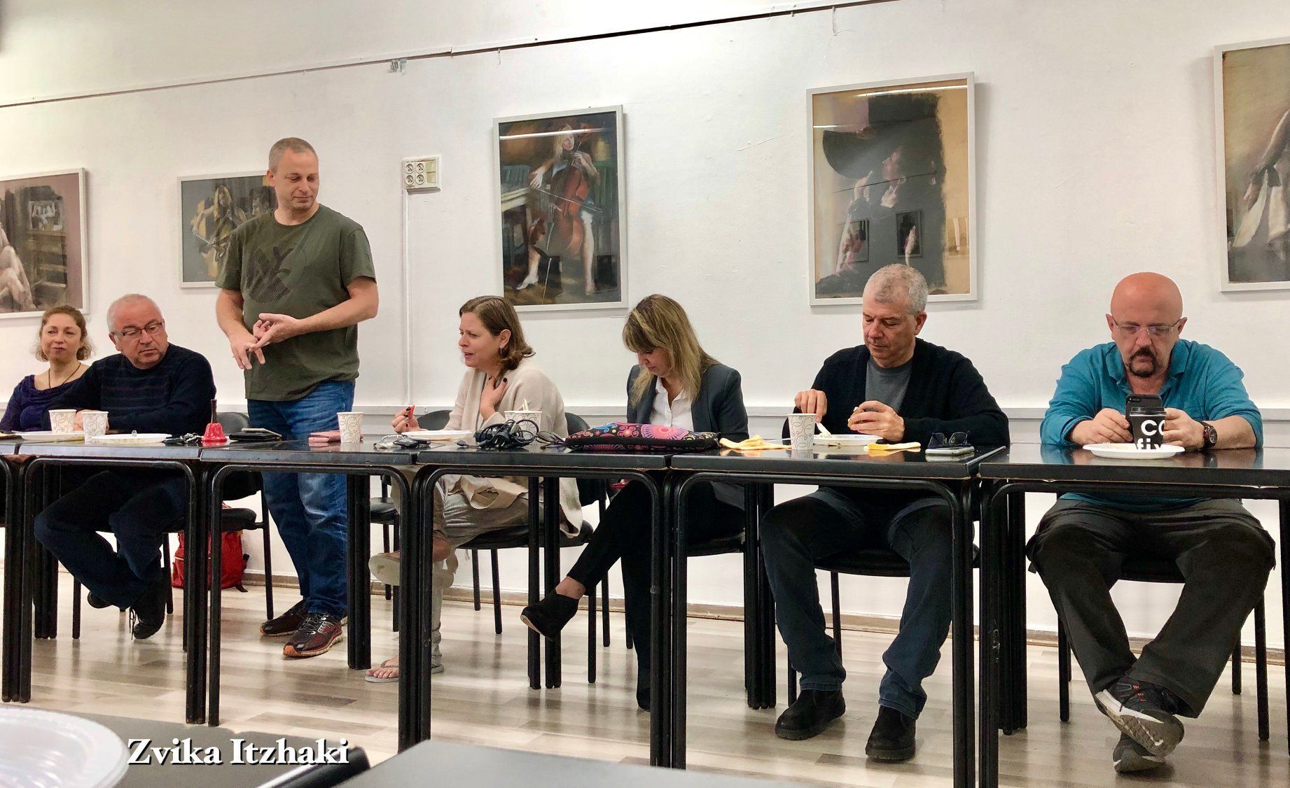 קבוצה של אנשים יושבת ליד שולחנות בחדר.