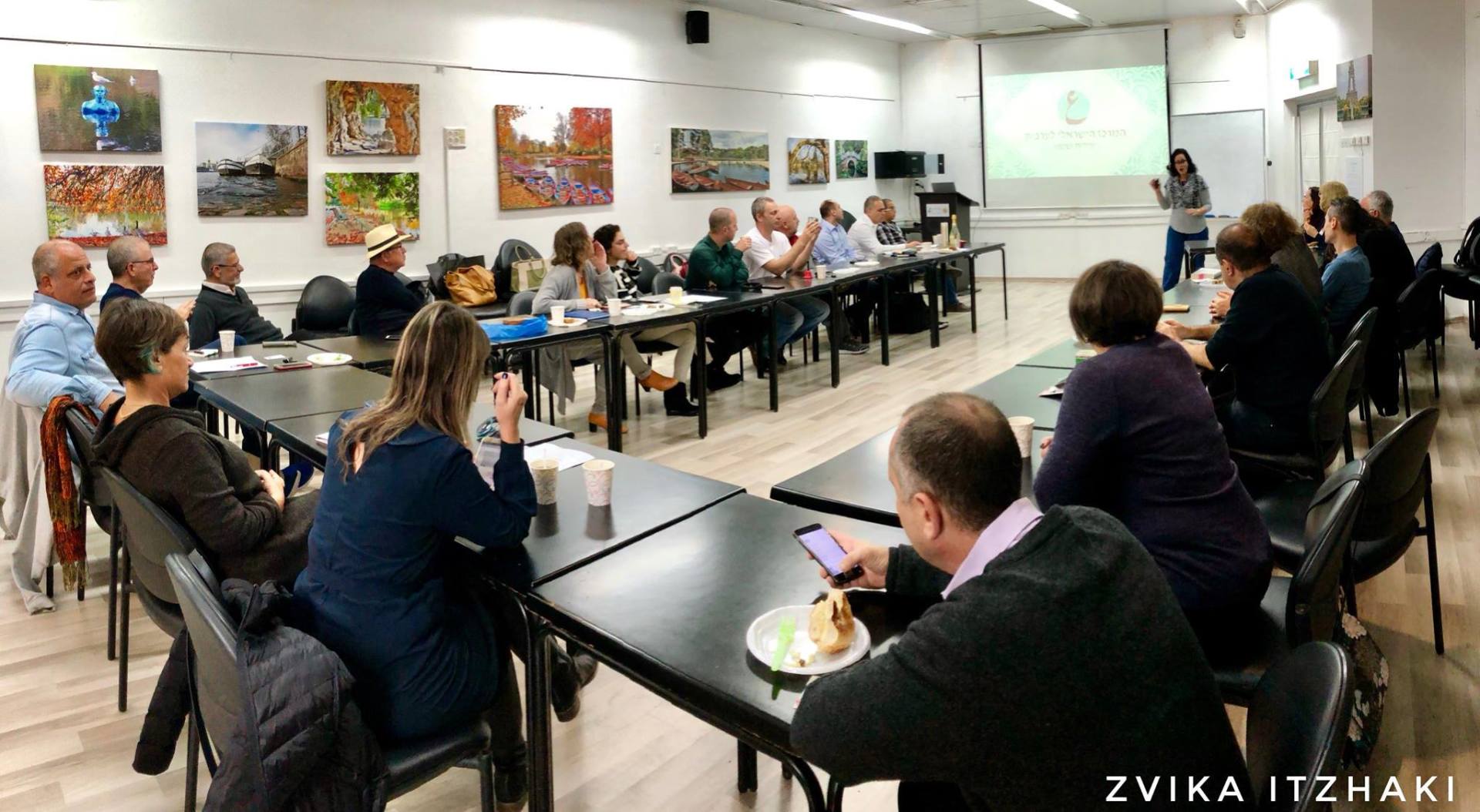 קבוצה של אנשים יושבת ליד שולחנות בחדר.