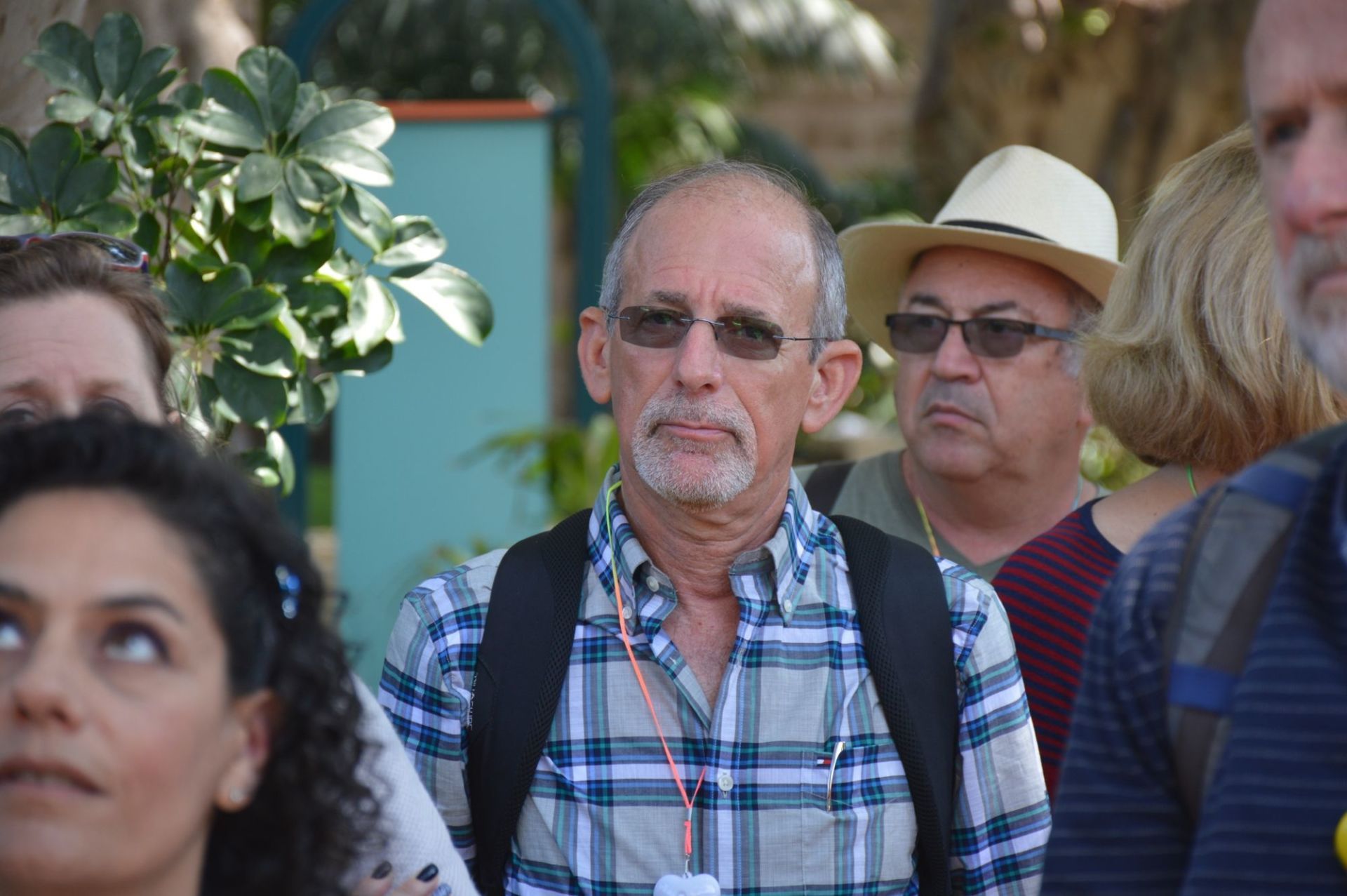 גבר בחולצה משובצת עומד בתוך המון אנשים.