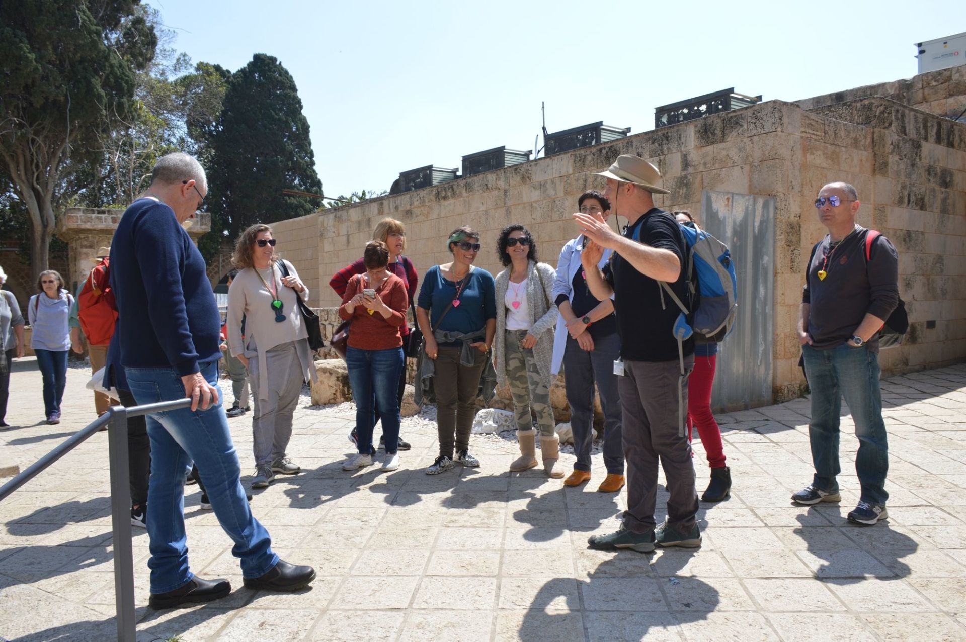 קבוצת אנשים עומדת מול חומת אבן.
