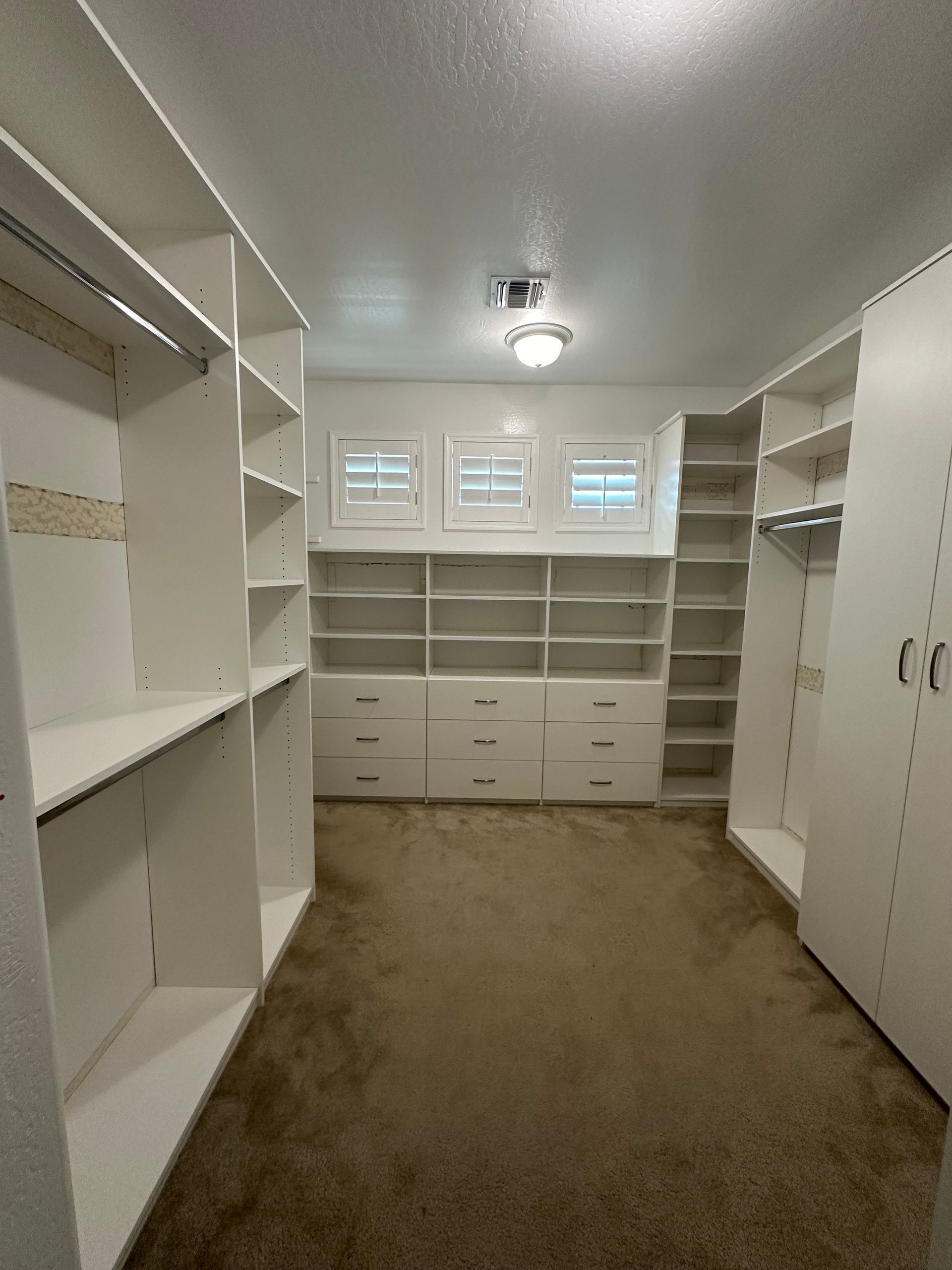 A large walk in closet with lots of shelves and drawers