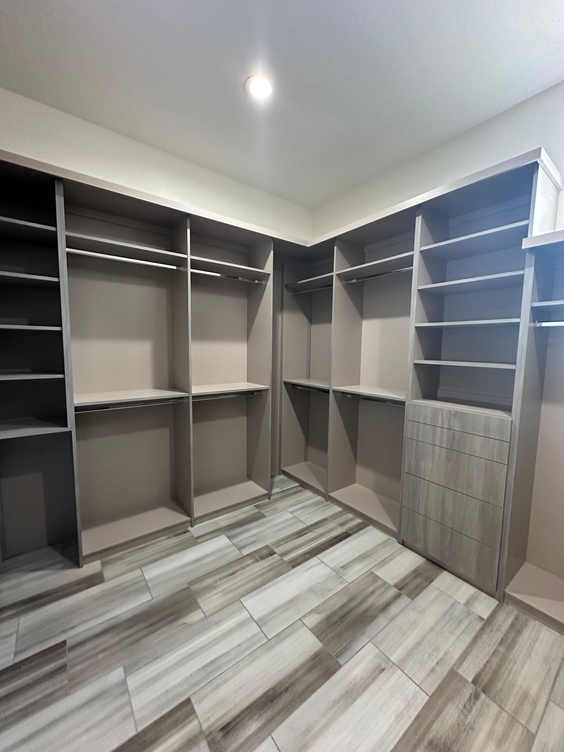 A walk in closet with lots of shelves and a tiled floor.