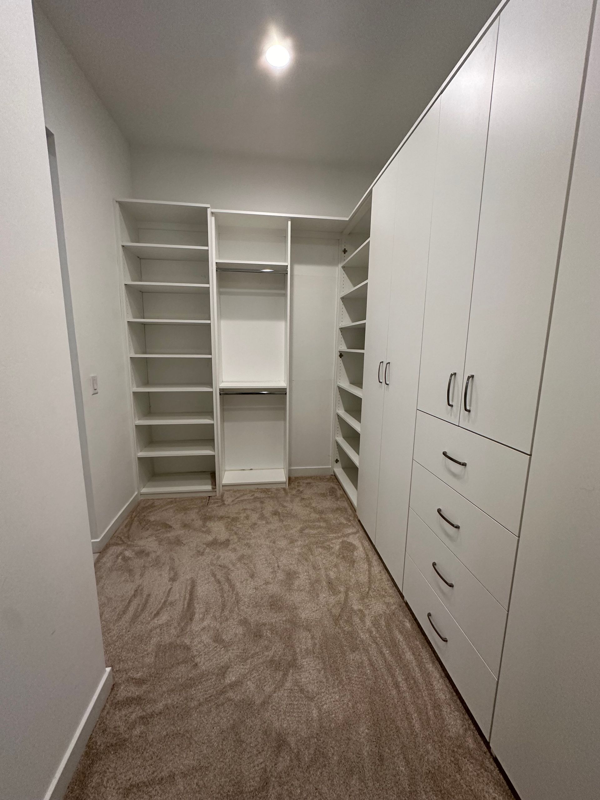 A walk in closet with lots of shelves and drawers.