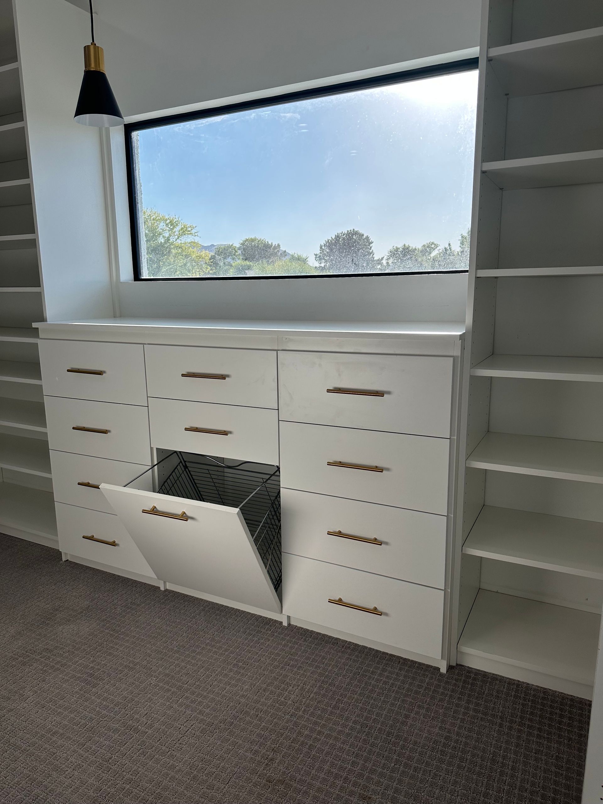 A room with lots of shelves and drawers and a window.