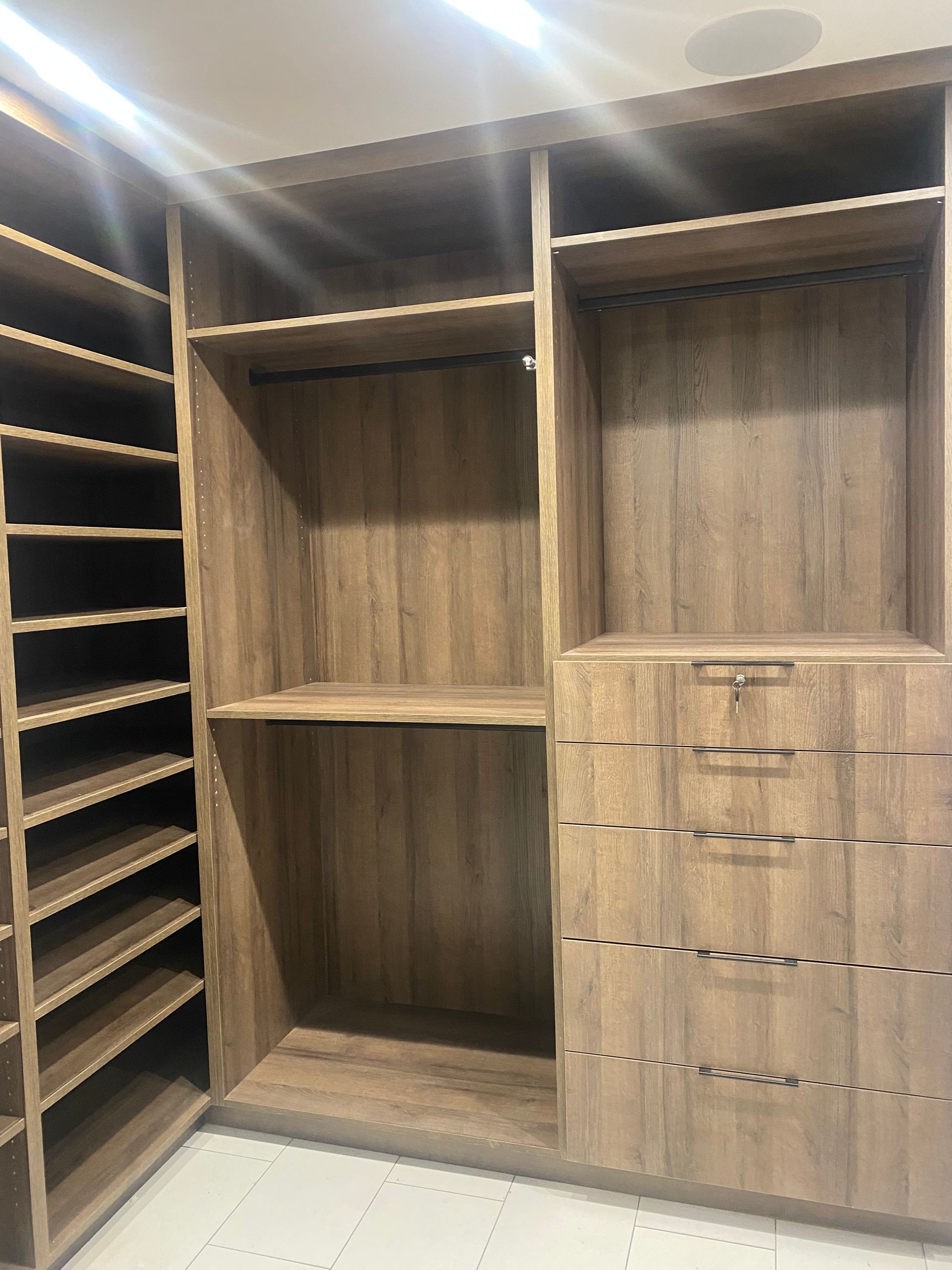 A walk in closet with lots of shelves and drawers.