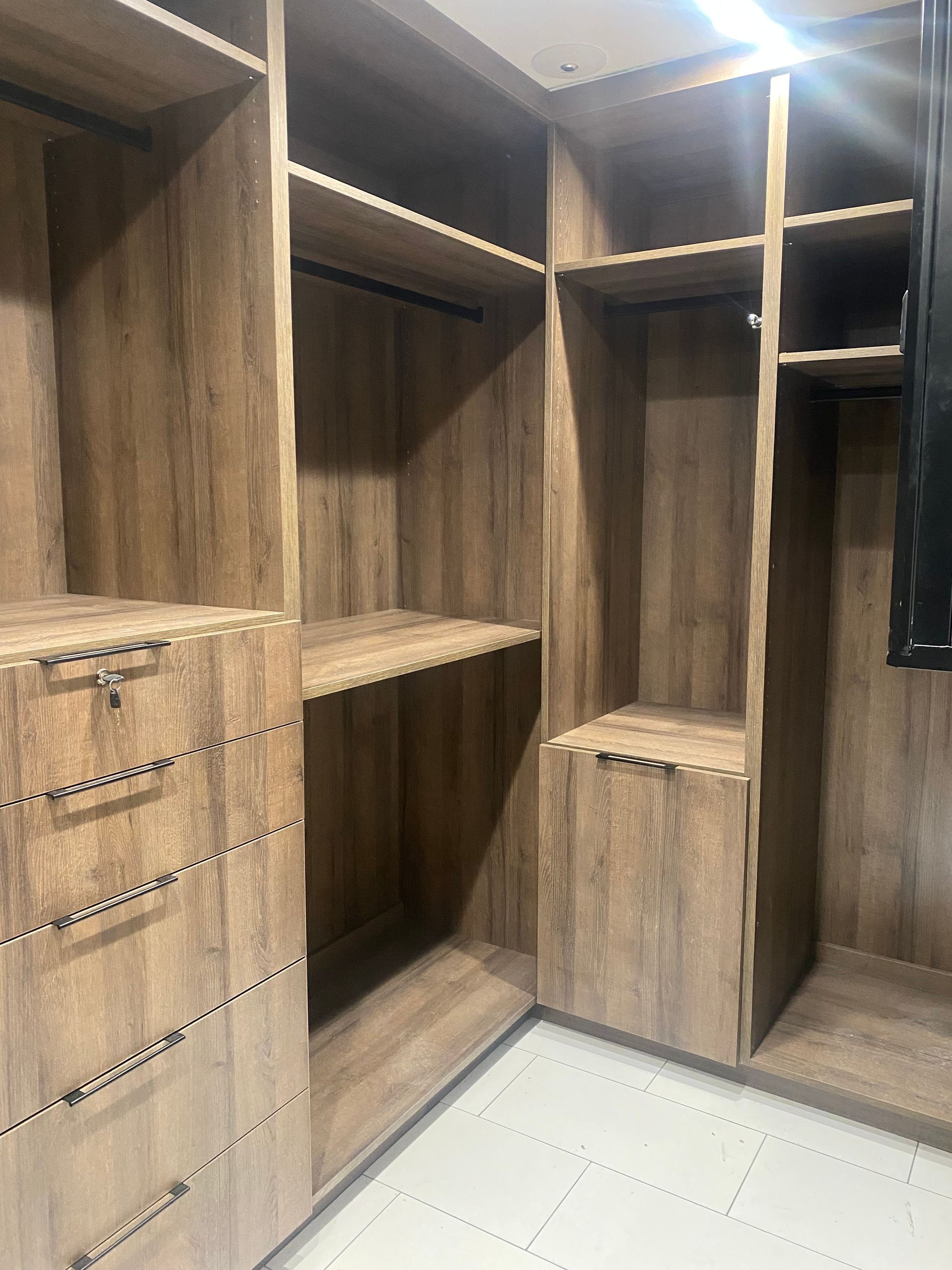A walk in closet with lots of wooden shelves and drawers.