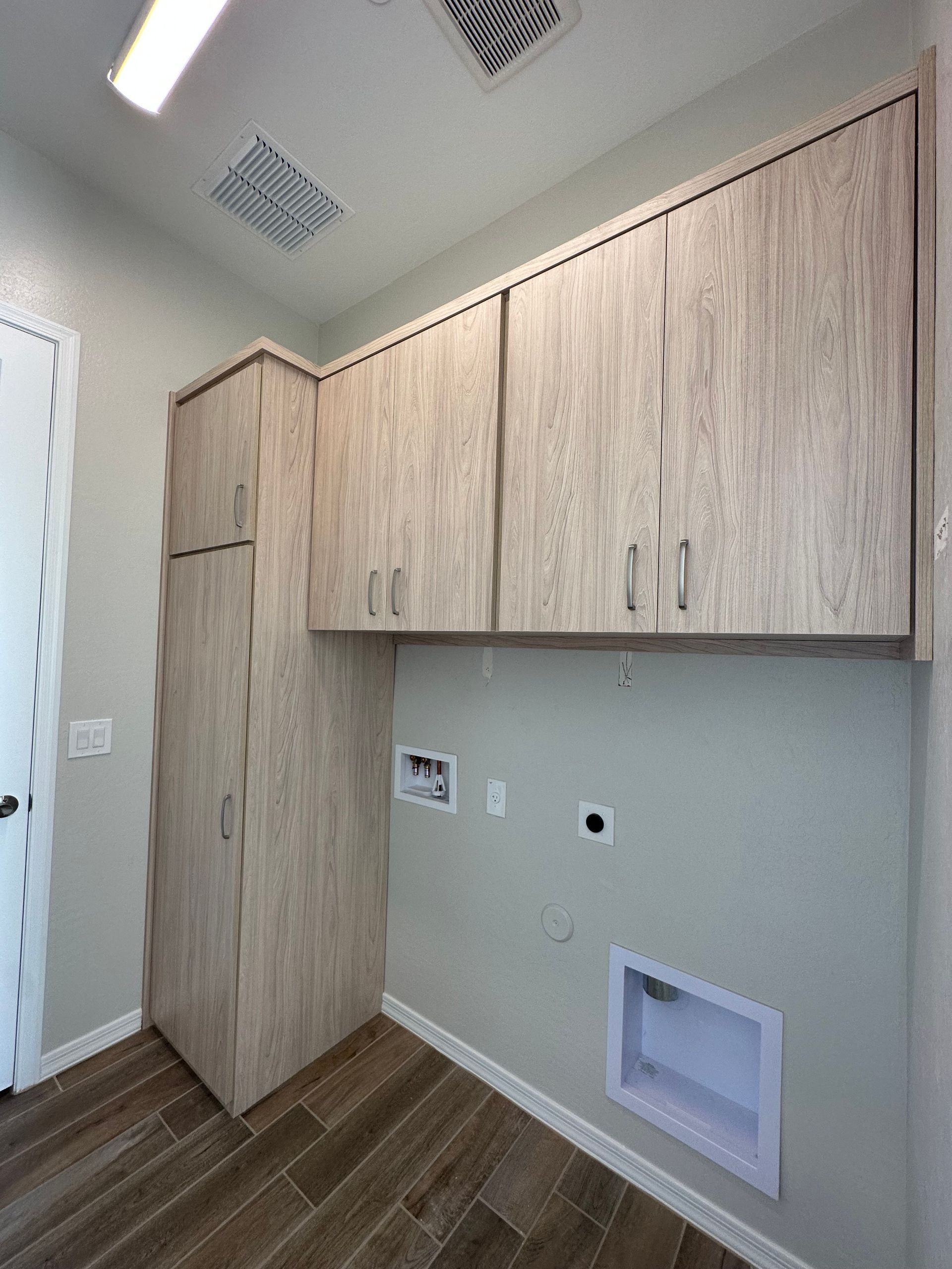 A laundry room with wooden cabinets and a washer and dryer.