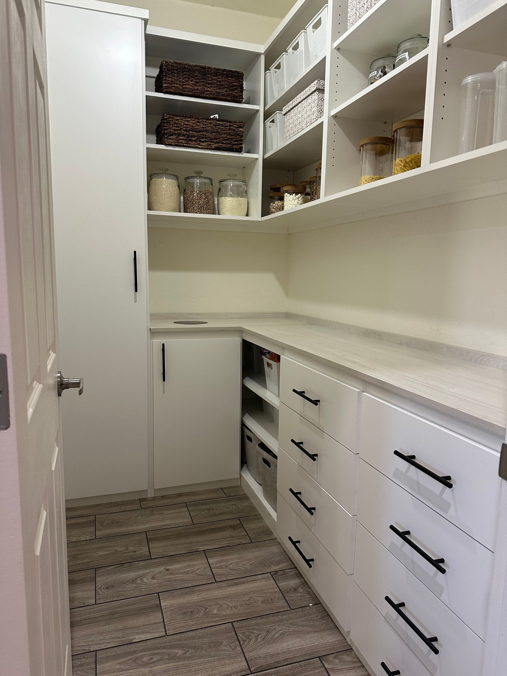 A pantry with lots of shelves and drawers and a door.