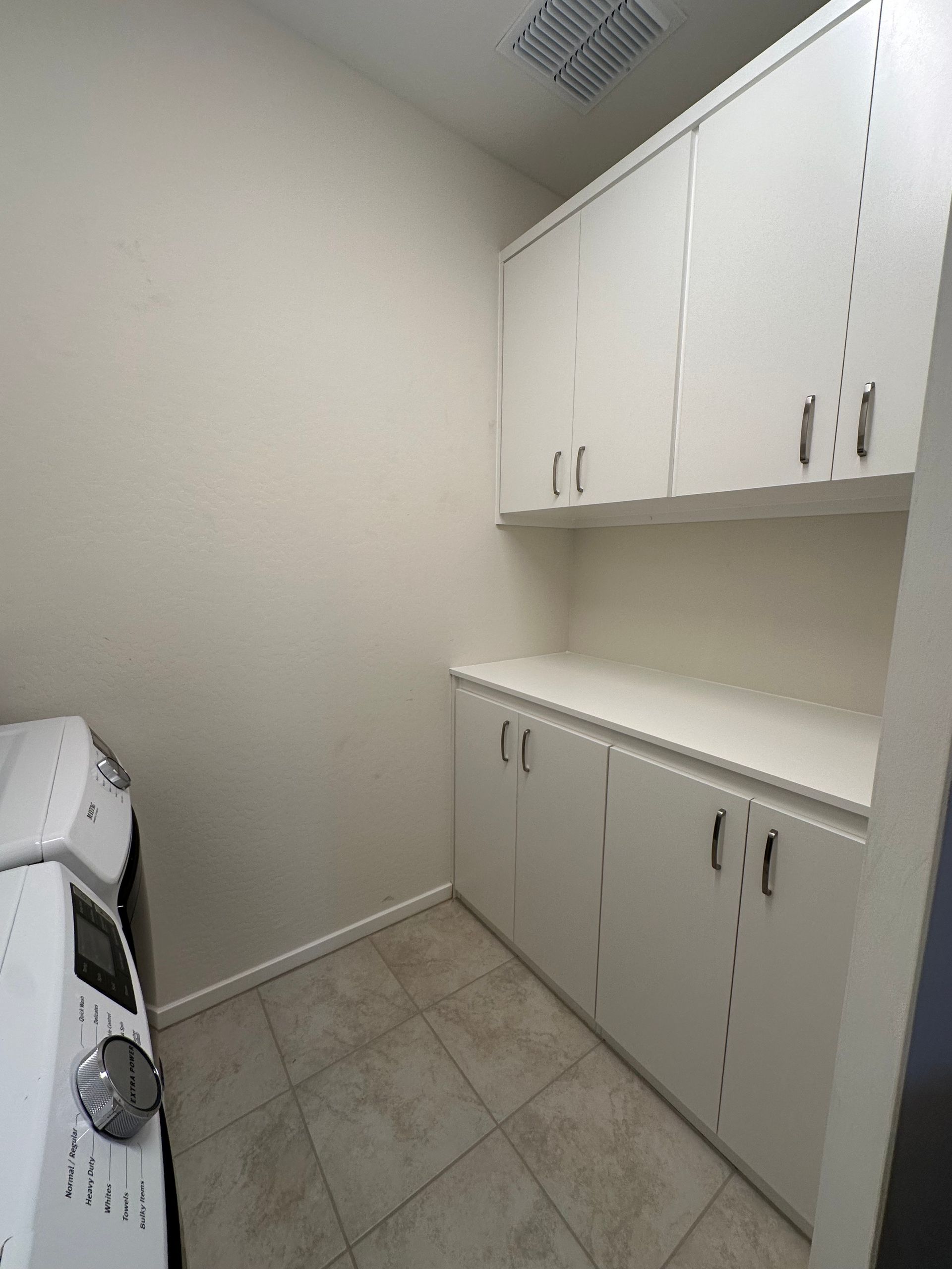 A laundry room with white cabinets and a washer and dryer