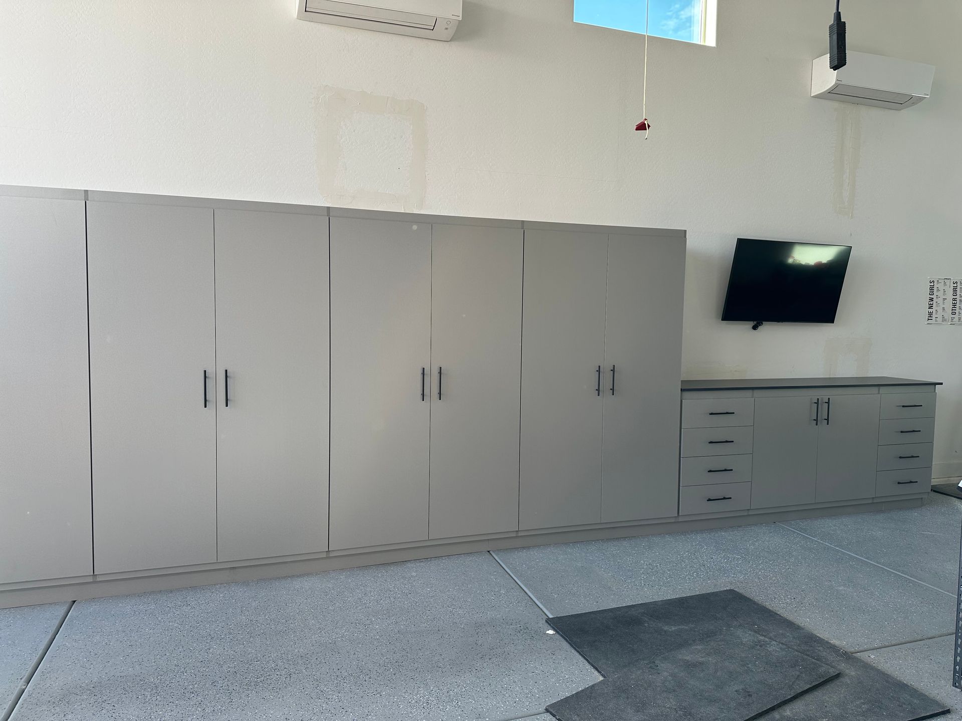 A garage with a lot of cabinets and a flat screen tv on the wall.