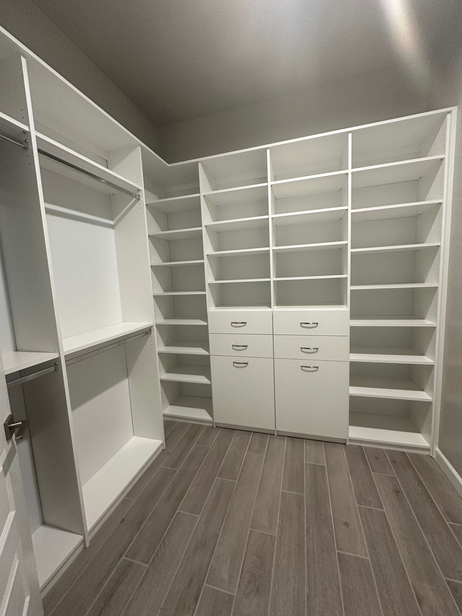 A walk in closet with lots of shelves and drawers.