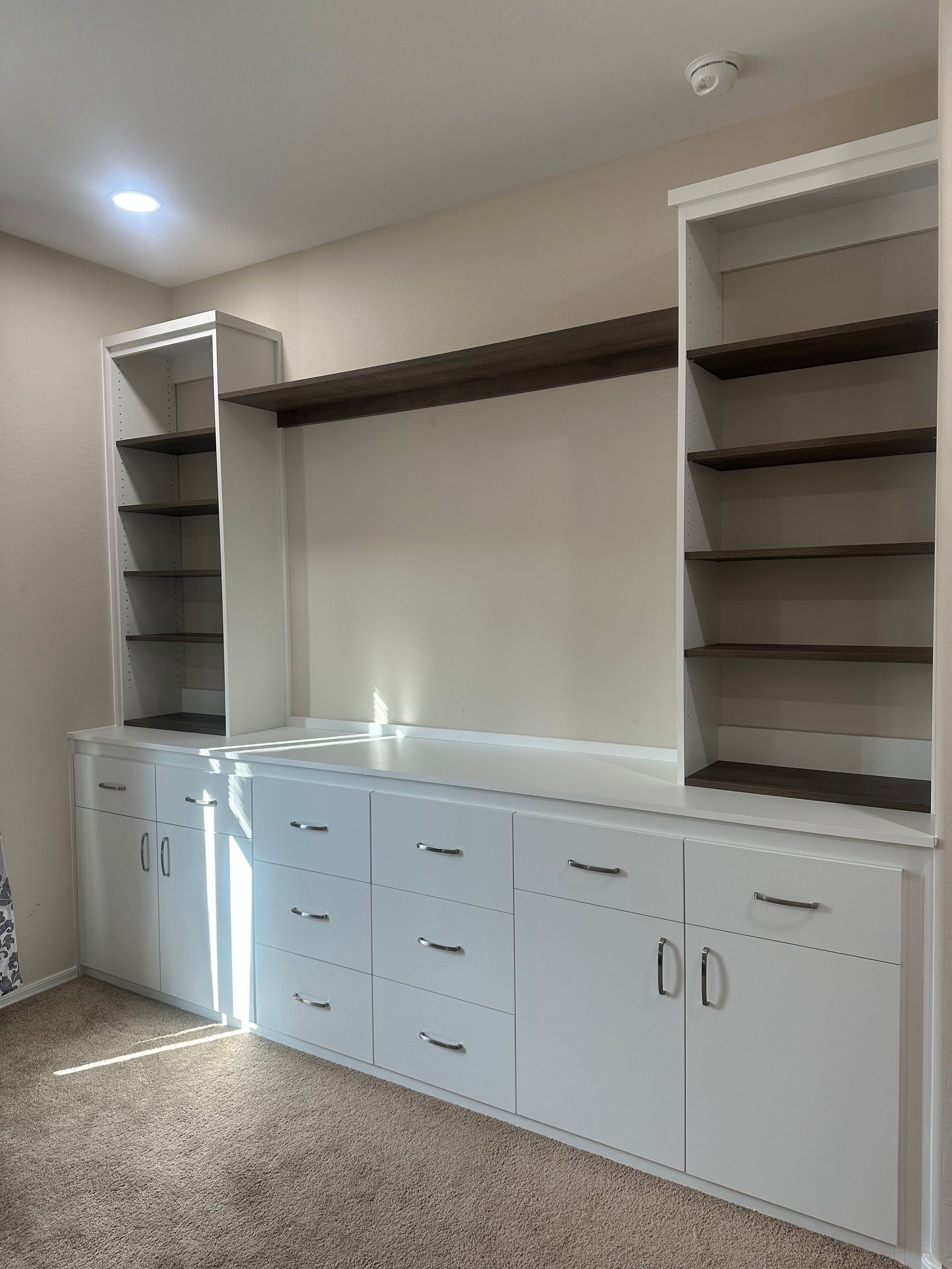 A room with white cabinets and shelves in it.