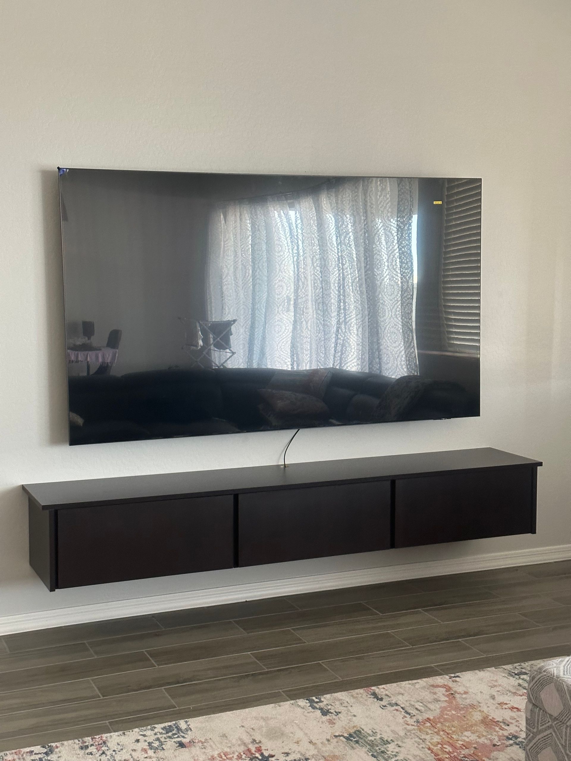 A flat screen tv is mounted on a wall above a wooden entertainment center.