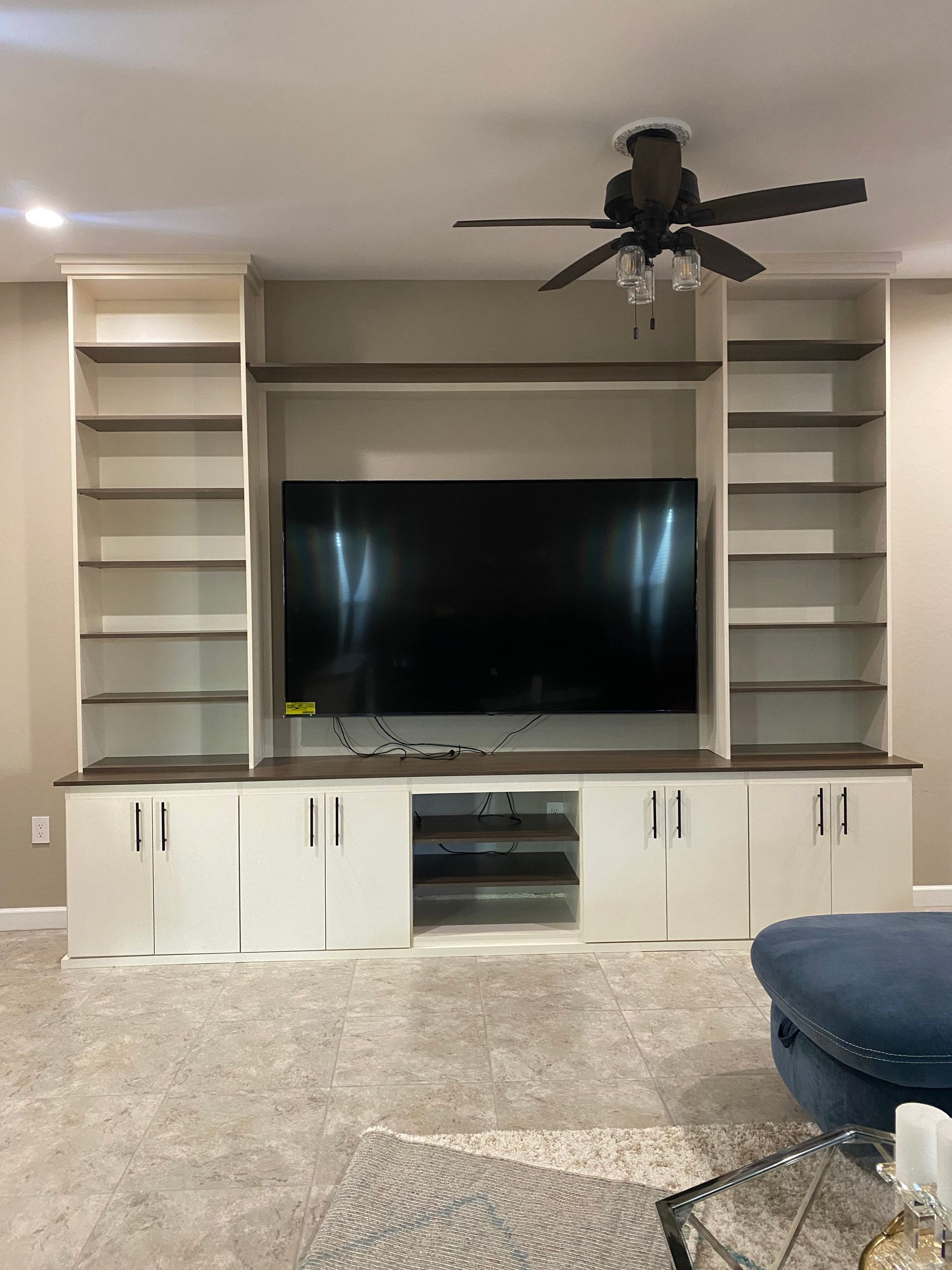 A living room with a flat screen tv and a ceiling fan.