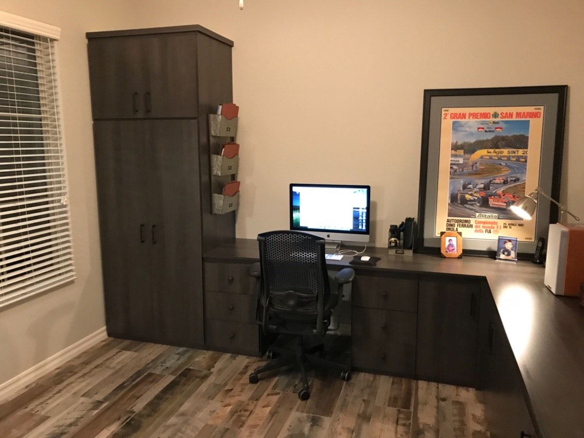 A desk with a computer on it in a room with a picture on the wall.