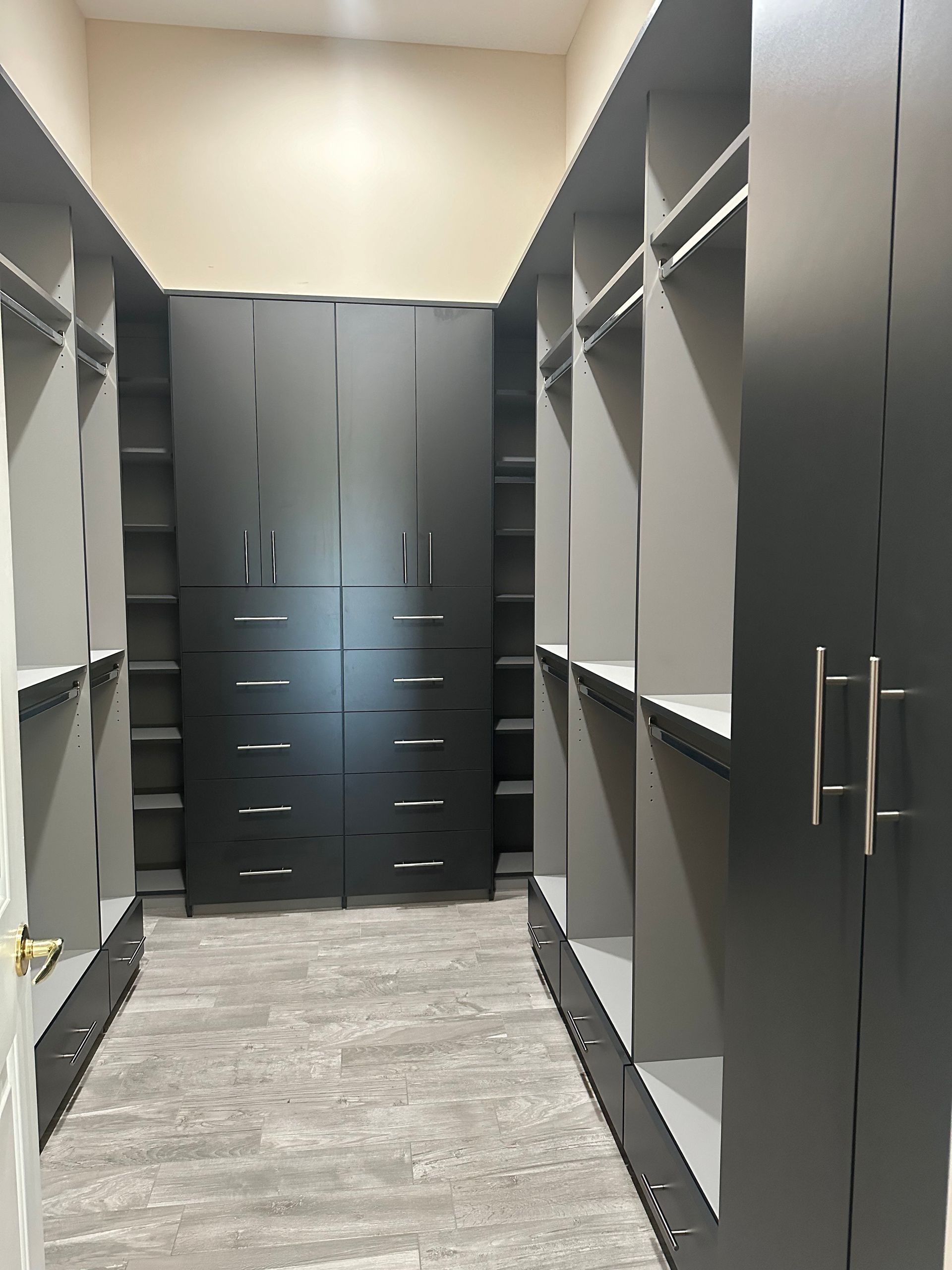 A walk in closet with lots of shelves and cabinets